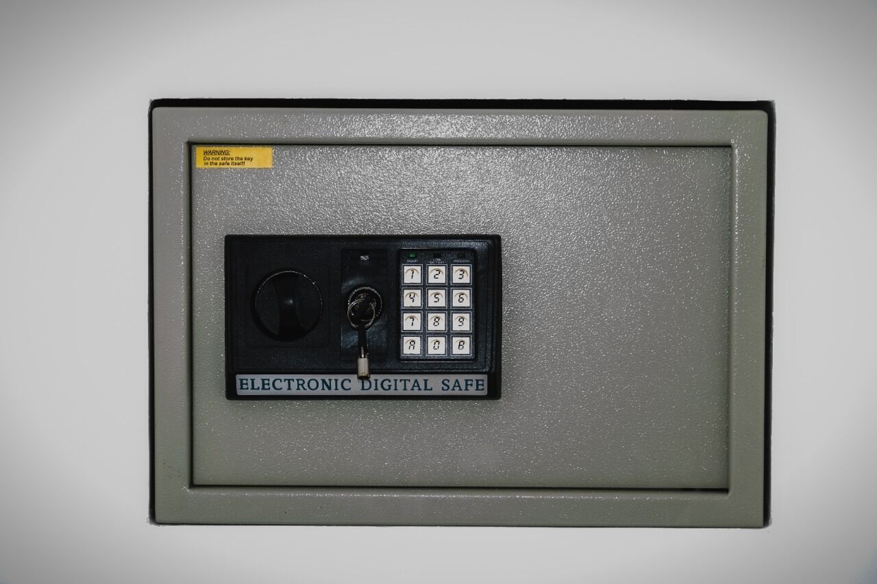 An electronic safe with a keypad and a warning label.