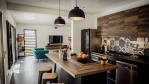 Eine moderne Küche mit einer Holzinsel, Pendelleuchten und einem schwarzen Kühlschrank.