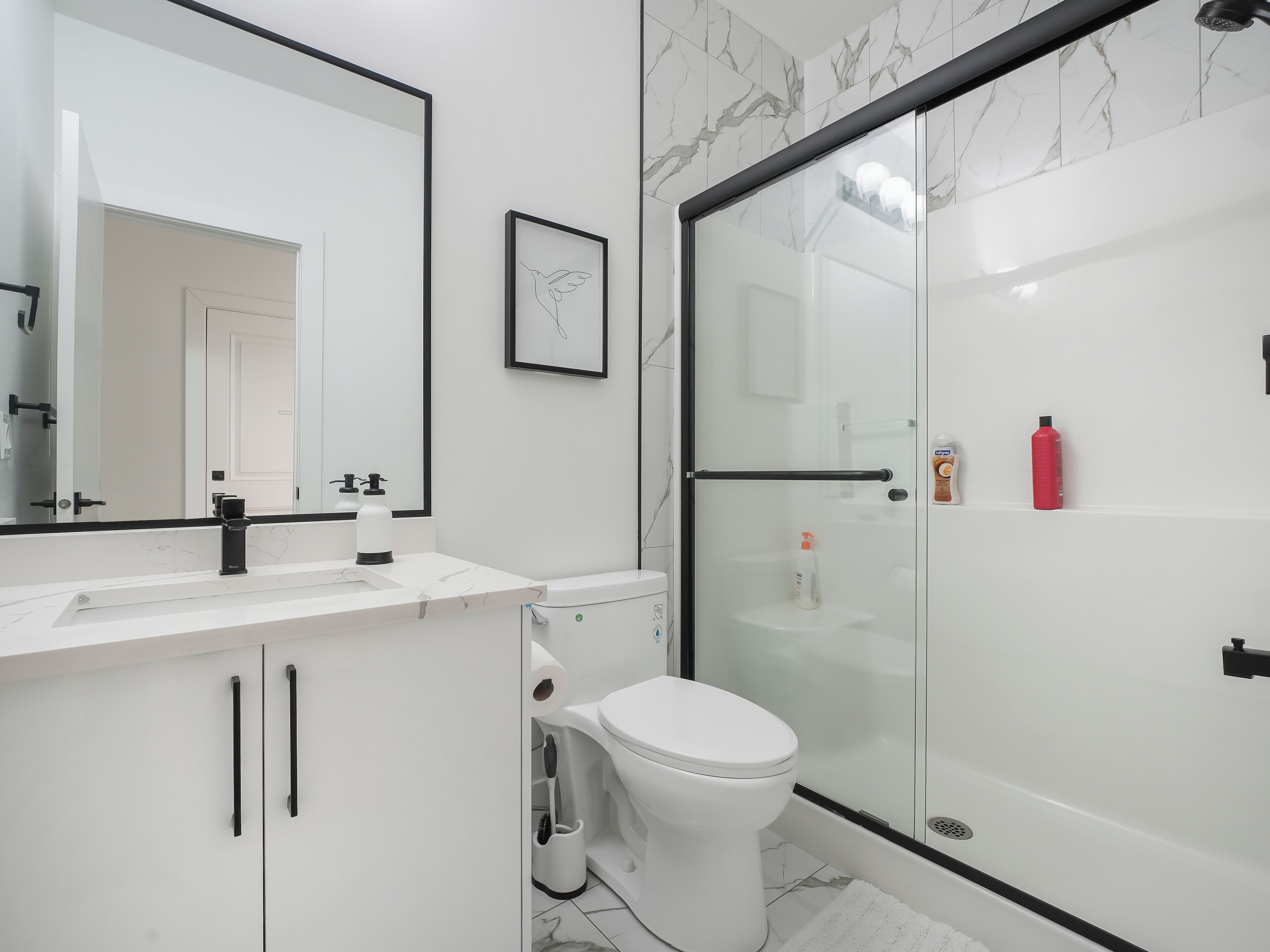 Une salle de bain moderne avec un lavabo blanc, des toilettes et une douche à parois de verre.