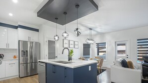 A modern kitchen with a central island, stainless steel appliances, and pendant lighting.