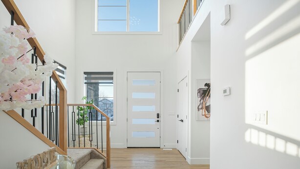 A modern interior with a staircase, a glass railing, and a door with frosted glass panels.