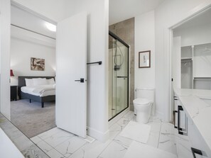 Ein modernes Badezimmer mit einer Duschkabine aus Glas, einer weißen Toilette und einem Marmorboden.
