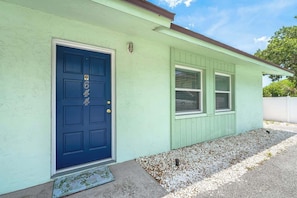 A house with a blue door, a number '64' on the door, and a small porch with a doormat.