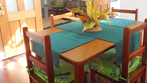 Un coin repas avec une table dressée pour quatre personnes, entourée de chaises en bois dotées de coussins verts.