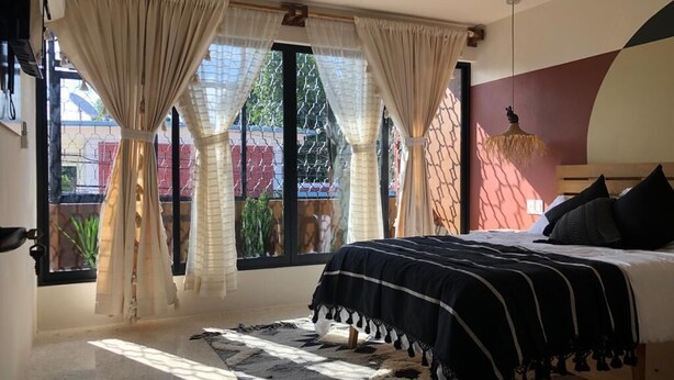 Ein Schlafzimmer mit Bett, Vorhängen und Blick ins Freie.