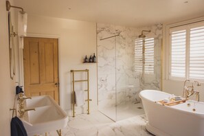 A bathroom with a freestanding bathtub, a shower with a glass door, and a wooden door.