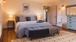 Ein Schlafzimmer mit einem großen Bett, Nachttischlampen, einem Schminktisch und einem Spiegel.