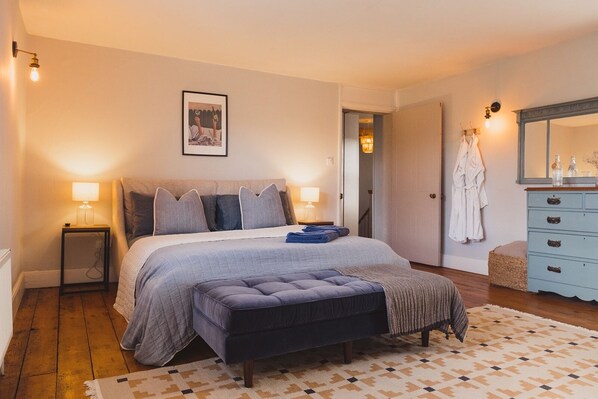 A bedroom with a large bed, bedside lamps, a dresser, and a mirror.
