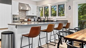 Une cuisine moderne avec des meubles blancs, un plan de travail en granit et un grand îlot central doté de tabourets de bar.