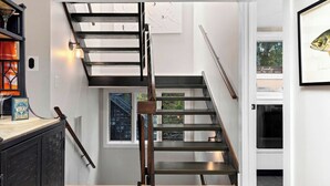 Un escalier moderne au design minimaliste, un plancher en bois et une vue sur l’extérieur par une fenêtre.