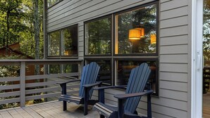 Une terrasse en bois avec des fauteuils Adirondack et une rambarde.