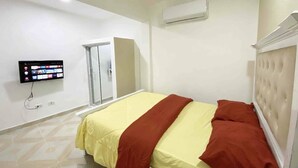 A bedroom with a bed, a television, and an air conditioning unit. - RA-4 cómodo apartamento con vista al mar (Samaná)