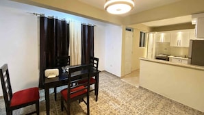 A compact living space with a dining area featuring a table and chairs, a kitchenette with cabinets, and a ceiling light fixture. - RA-4 cómodo apartamento con vista al mar (Samaná)
