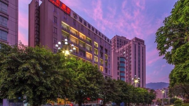 A hotel with multiple floors, large windows, and a prominent sign with red text. - Senlian City Express Hotel (Qingyuan Gulongxia City Beiqi Station Store) (Qingyuan)