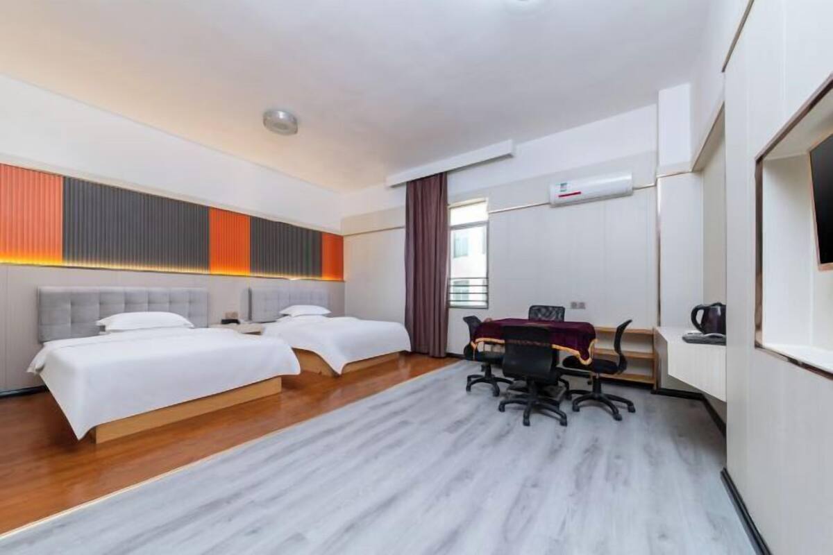 Une chambre d’hôtel avec deux lits, un bureau et une chaise.