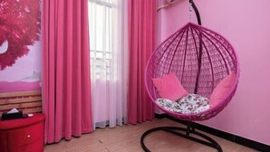 A room with a hanging pink chair, a red dresser, and a pink wall. - Senlian City Express Hotel (Qingyuan Gulongxia City Beiqi Station Store) (Qingyuan)