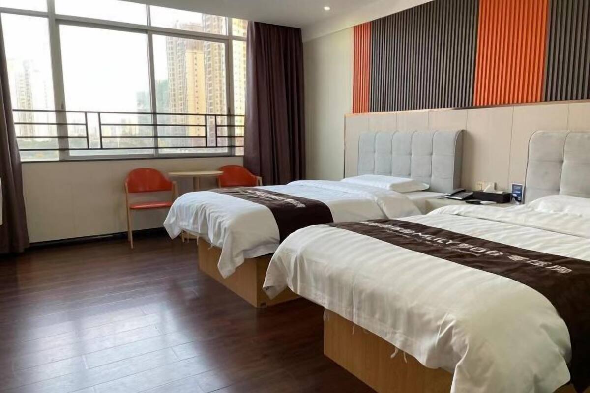 Une chambre d’hôtel avec deux lits, un bureau et une fenêtre donnant sur des immeubles.
