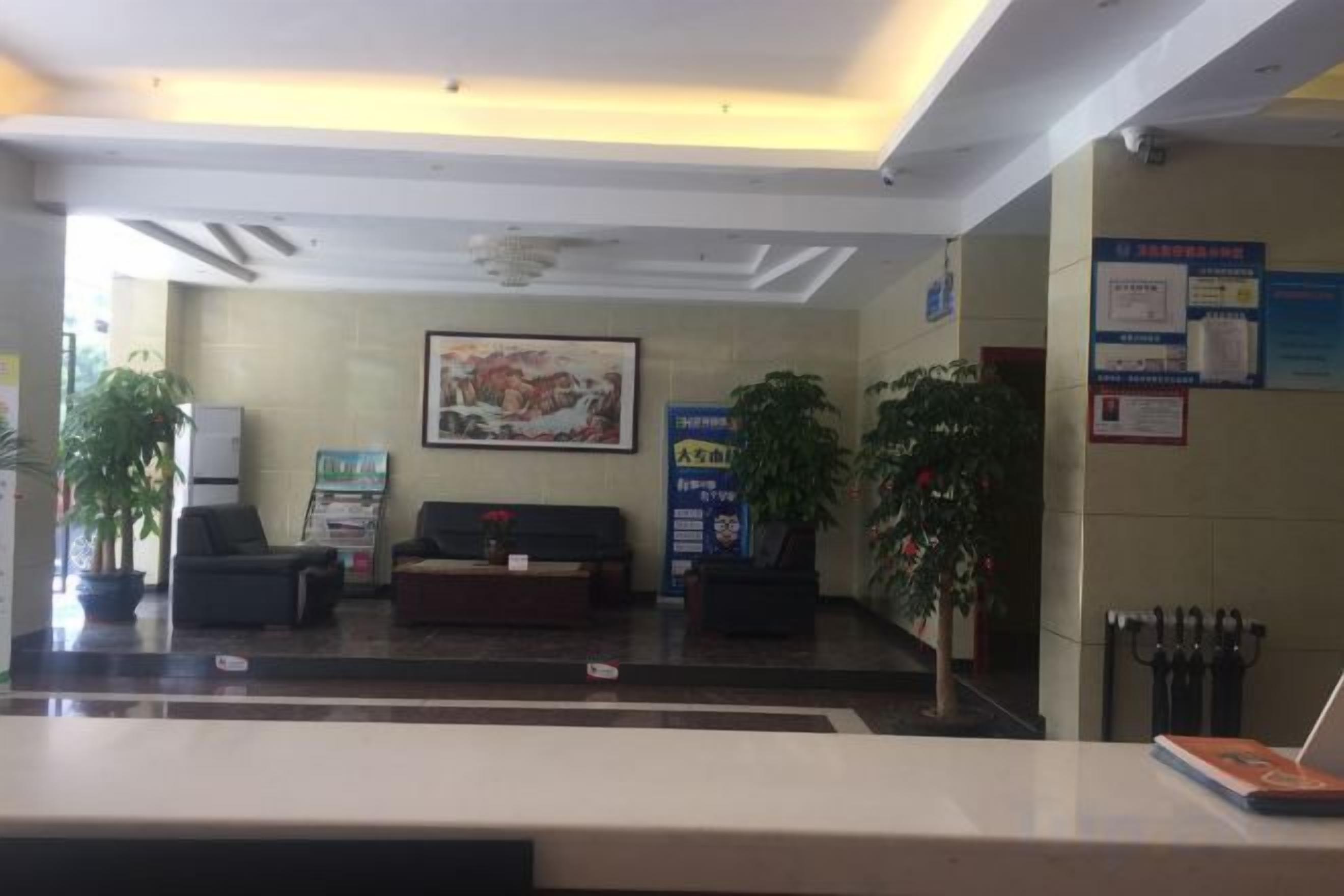 A reception area with a reception desk, seating, a large painting, and informational posters on the walls.