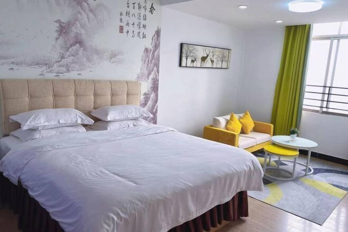 Une chambre d’hôtel avec un grand lit, un canapé, une petite table et un tableau au mur.