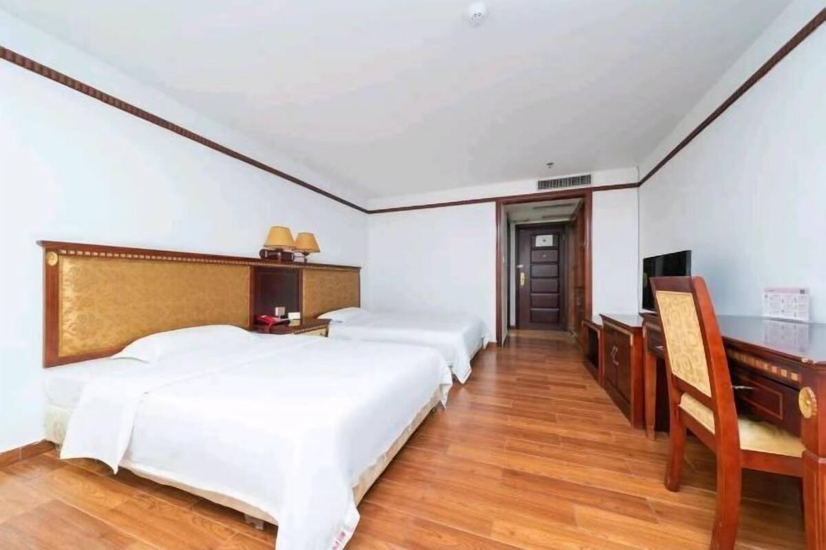Une chambre d’hôtel avec deux lits, un bureau, une chaise et un téléviseur.