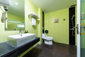 Une salle de bain avec un lavabo blanc, des toilettes et un espace douche.
