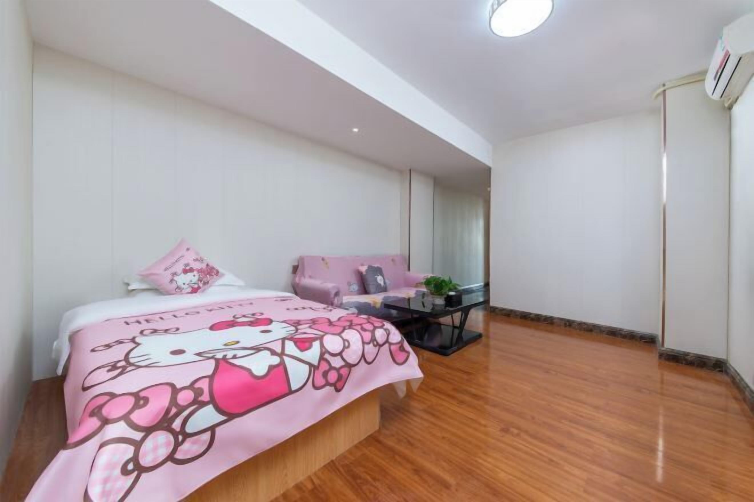 A bedroom with a bed, a sofa, a small table, and a potted plant.