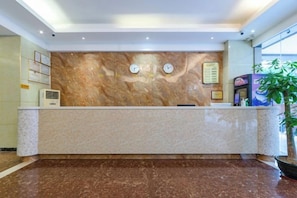 A hotel reception area with a marble counter, clocks, and a menu board. - Senlian City Express Hotel (Qingyuan Gulongxia City Beiqi Station Store) (Qingyuan)