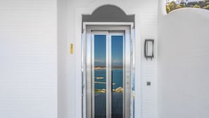 Un edificio blanco con un acceso de doble puerta que da a un balcón con vistas al mar.