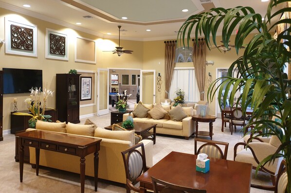 Relax in this stylish living room with a sofa, coffee table, and dining area, featuring a flat-screen TV and a large potted plant.