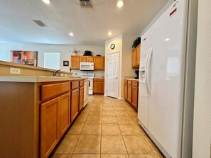 Enjoy cooking in this well-equipped kitchen with a central island, refrigerator, and tiled floor.