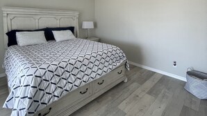 A bedroom with a bed, a nightstand, a lamp, a ceiling fan, and a pet bed.