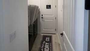 A hallway with a door marked "no entry" and a mat that reads "laundry same day service".