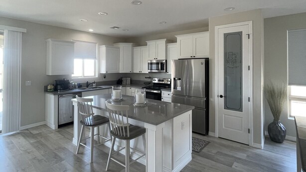 A spacious kitchen with a large island, white cabinetry, and stainless steel appliances.