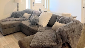 A living room with a sectional sofa, a lamp, and a ceiling fan.