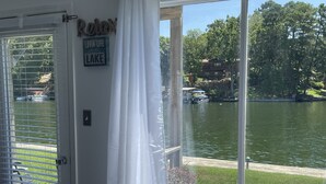 Una habitación con un ventanal grande que da a un lago, una puerta con un letrero que dice 'Relax' y un letrero en la pared que dice 'Lovin' Life at the Lake'.