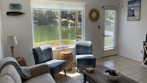 Una sala de estar con vista a un lago, dos sillones, un sofá, una mesa de centro y una lámpara.