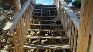 Una escalera de madera con barandilla que lleva a una zona cubierta.