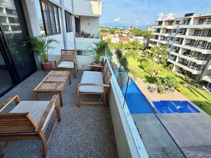 A balcony with wooden furniture, a small pool, and a view of a residential area.