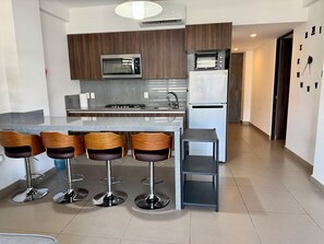 Une cuisine moderne dotée d’un îlot central, de tabourets de bar, d’un four à micro-ondes, d’un four encastré et d’un réfrigérateur.
