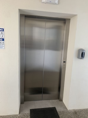 A closed elevator door with a hand sanitizer dispenser on the wall.