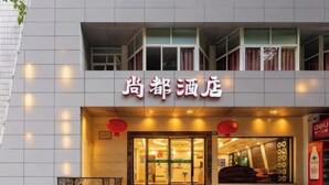 Entrada de um hotel com uma placa que diz "尚都酒店".