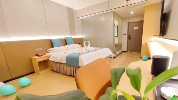 Quarto de hotel com cama, mesa de cabeceira e uma planta.
