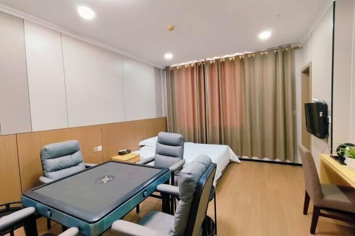 A hotel room with a bed, a desk, a chair, a table, and a television.