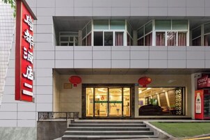 A hotel entrance with a red sign, a glass door, and a staircase leading up.