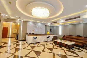 A hotel lobby with a reception desk, a chandelier, a marble wall, and a patterned floor. - Shangdu Hotel (Chongqing)