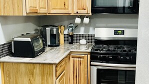 A kitchen with wooden cabinets, a microwave, a toaster, a kettle, and a stove. - Private apartment in our home with separate entry. (Valdez)