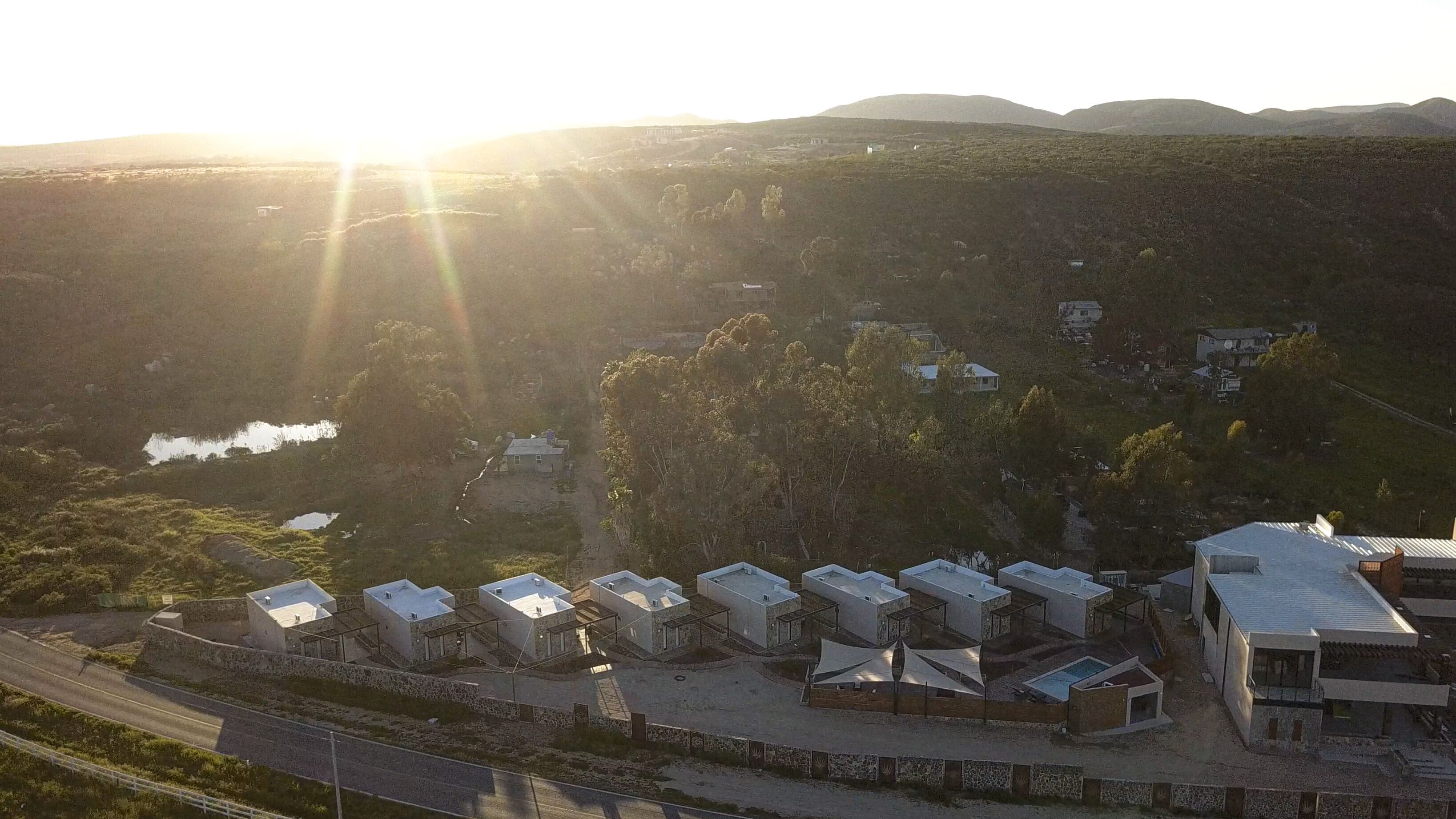 A residential area with multiple detached houses, a swimming pool, and a road in the foreground.