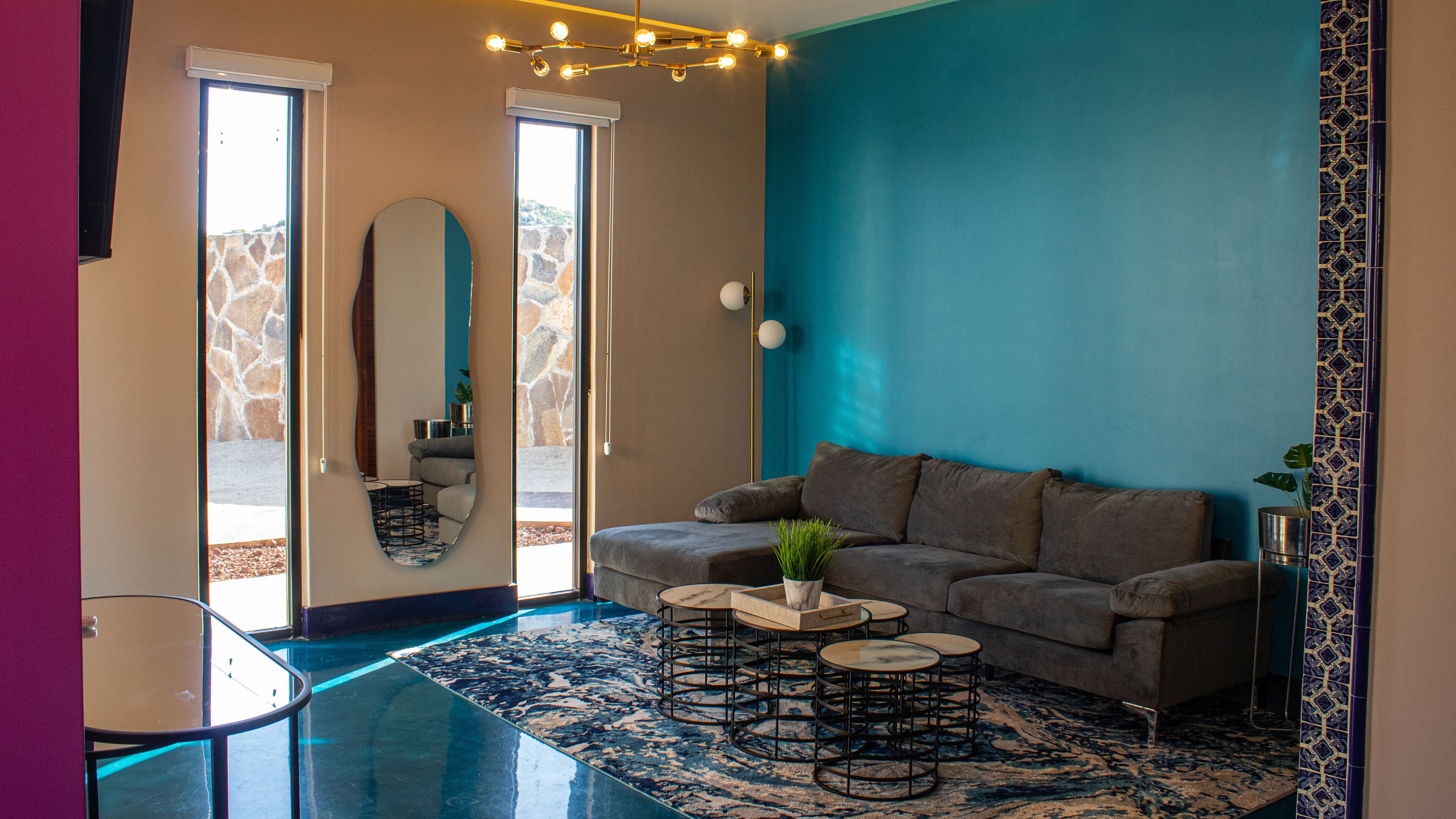 Una sala moderna con un sofá gris, una mesa de centro y una pared azul de acento.