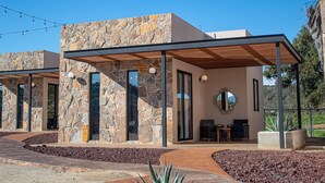 Un edificio moderno con fachada de piedra, ventanas grandes y una zona de estar al aire libre cubierta.