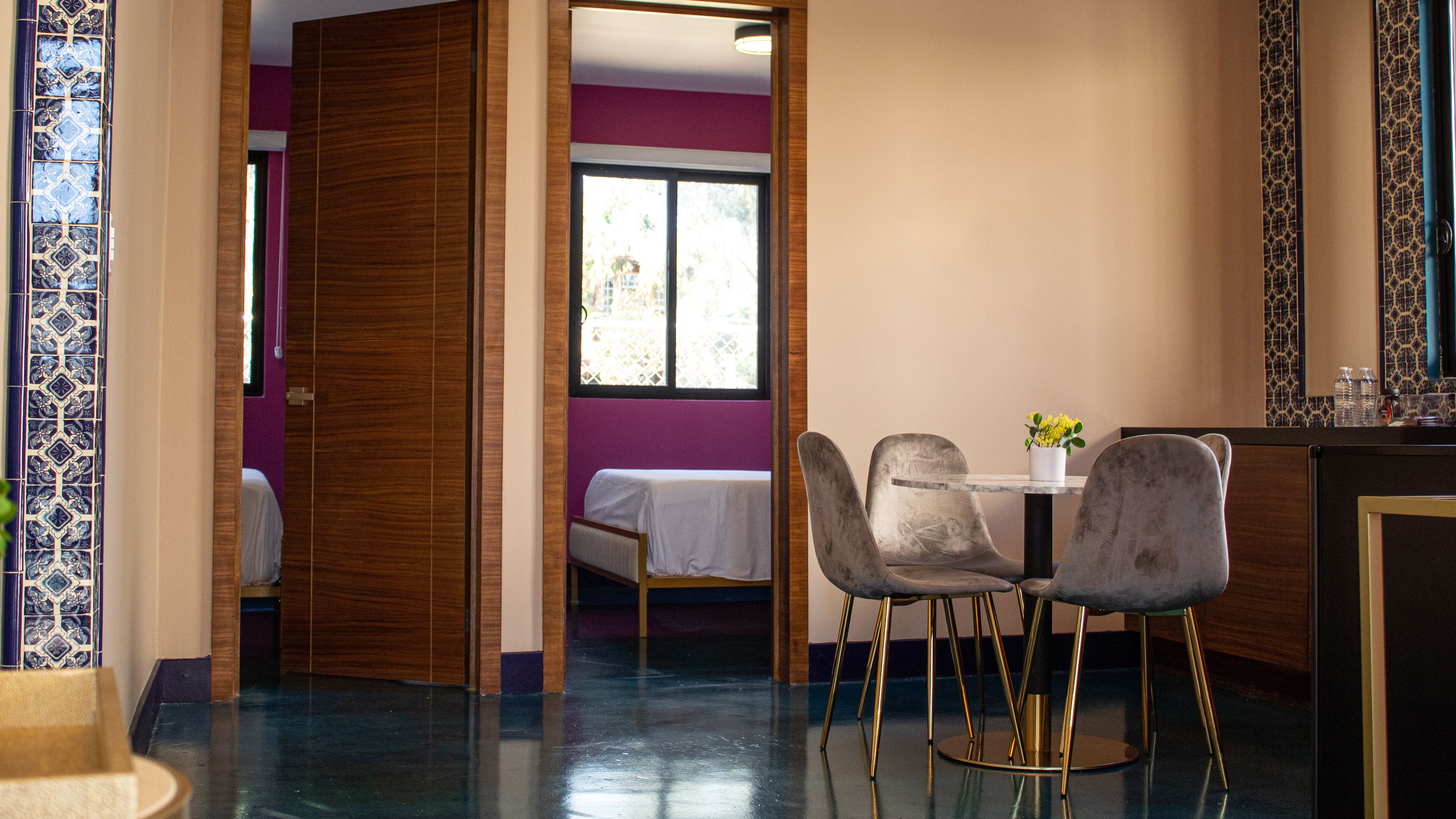 A hotel room with a bed, a dining table with two chairs, and a window with a view of the outside.